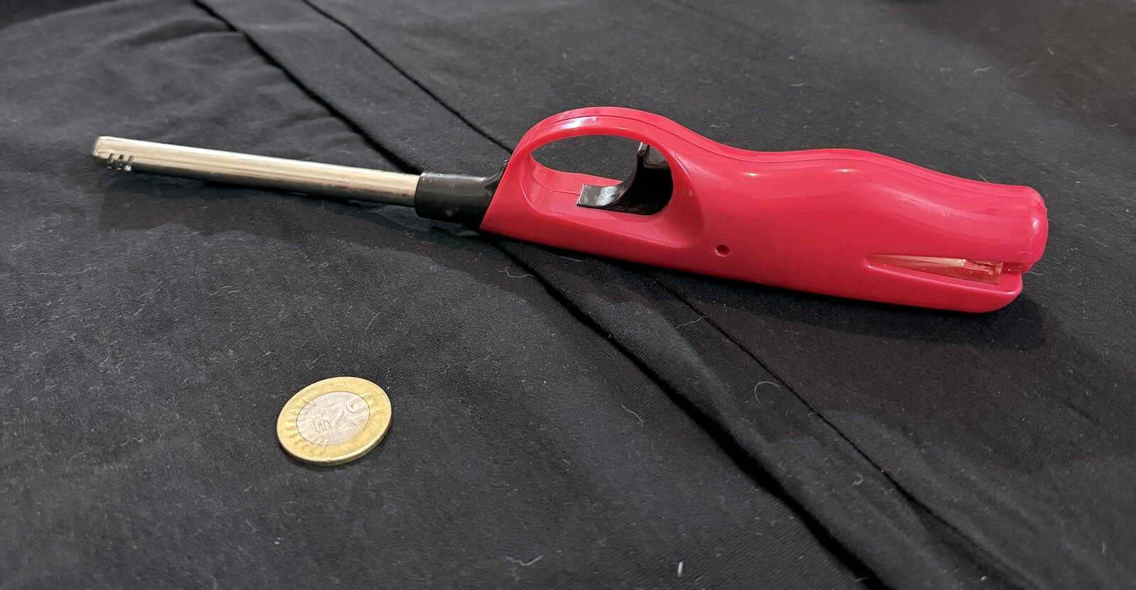 Real kitchen lighter photographed on black fabric with a coin for scale